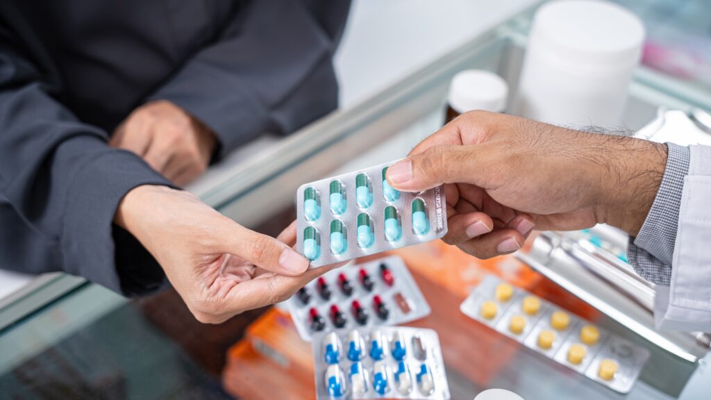 Close up hands of male pharmacist and female customer buying medicine in the pharmacy drugstore, hand over capsule pills of medicine from hand to another hand charge.