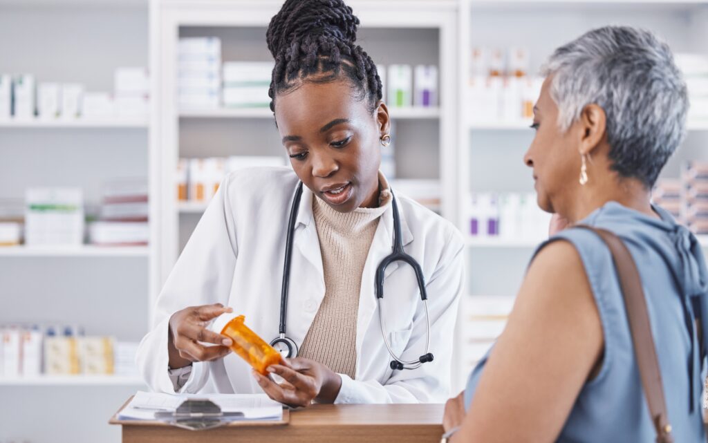 Doctor and prescription medication for patient or over the counter pills at pharmacy. African medical pharmacist consulting senior client for dosage, symptoms or side effects at clinic.